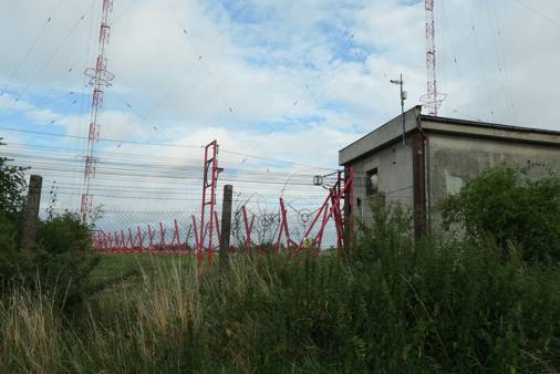 Anténní domek, kde se napájecí anténní vedení od vysílačů rozděluje a signál správně přizpůsobuje pro oba 355 m vysoké stožáry. Datum: 17.07.2021.
